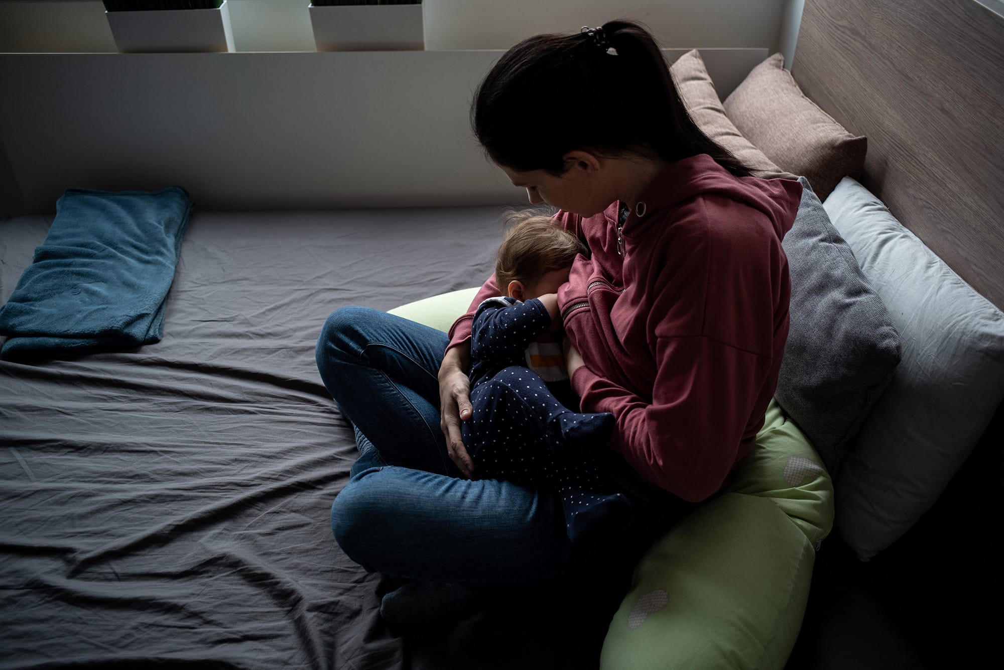Mother breastfeeding child in bedroom